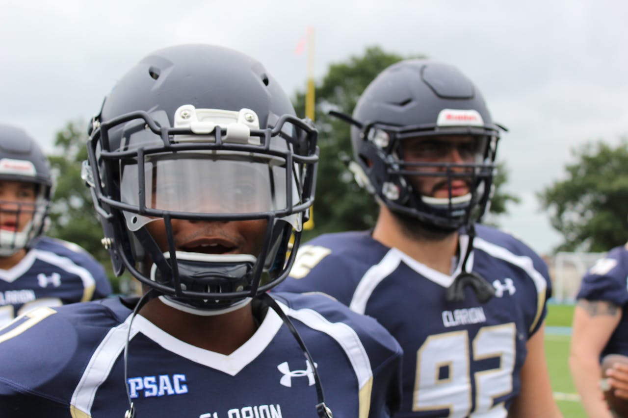 who-we-are Close-up of American football players in action, wearing helmets and jerseys, showcasing team spirit.