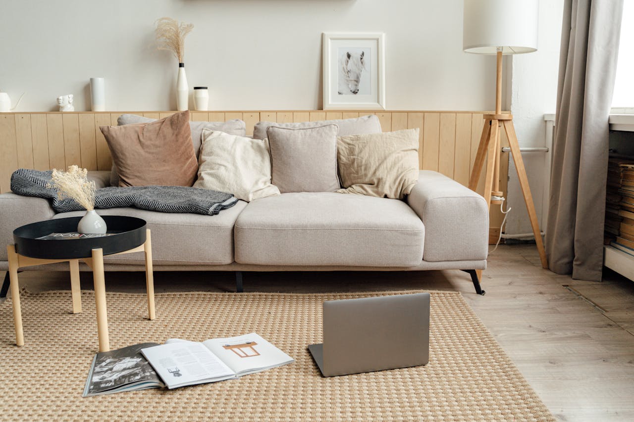 about-us A contemporary living room featuring a sofa, laptop, and modern decor, ideal for remote work.